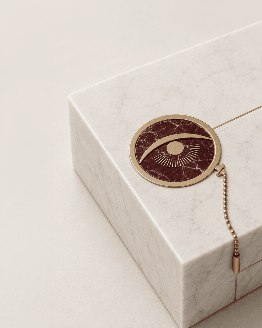 Gold-and-burgundy eye medallion resting on white marble